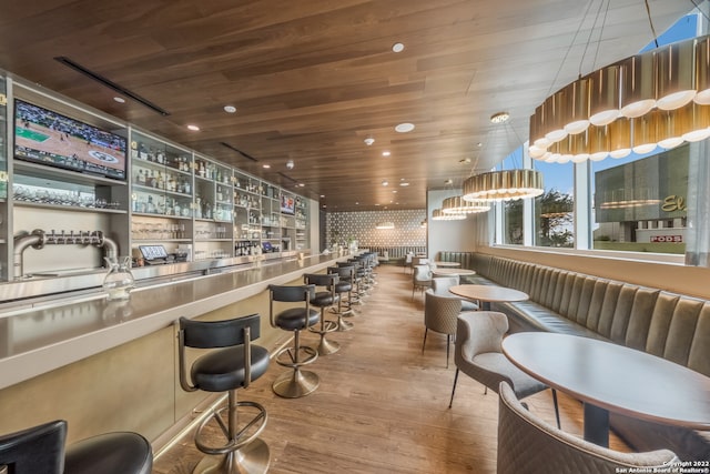 bar with stainless steel counters, hardwood / wood-style flooring, and wood ceiling