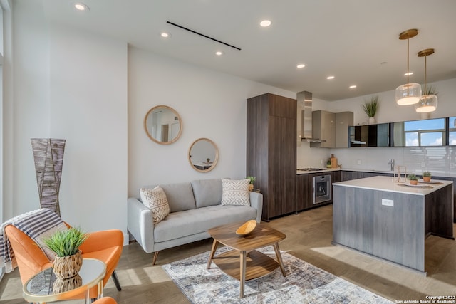 kitchen featuring dark brown cabinetry, wall chimney exhaust hood, backsplash, and light hardwood / wood-style flooring