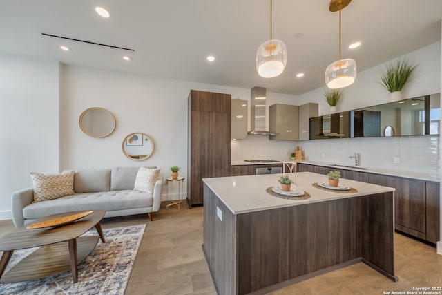 kitchen with dark brown cabinetry, sink, tasteful backsplash, wall chimney range hood, and light hardwood / wood-style floors