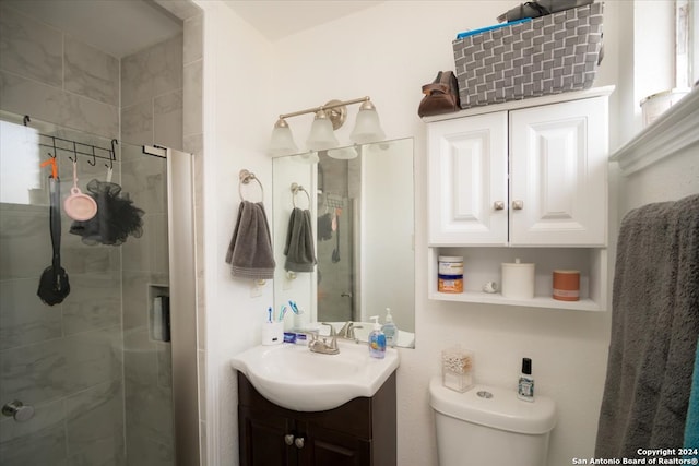 bathroom featuring a shower with shower door, vanity, and toilet