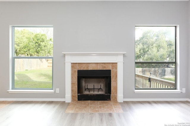 unfurnished living room with a tile fireplace and plenty of natural light