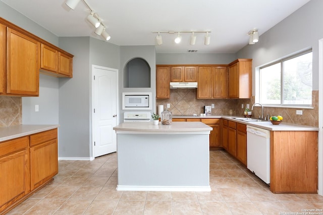 kitchen with tasteful backsplash, white appliances, sink, light tile patterned floors, and a kitchen island