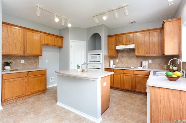 kitchen with decorative backsplash, a center island, white appliances, and sink