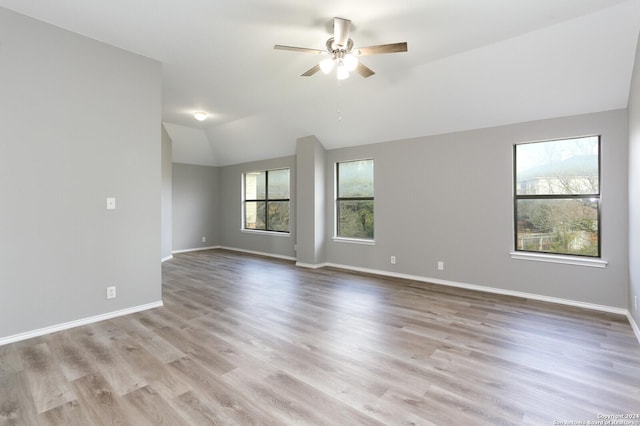 spare room with ceiling fan, light wood-type flooring, and vaulted ceiling