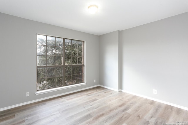 empty room with plenty of natural light and light hardwood / wood-style flooring