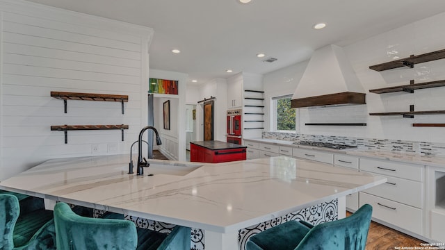 kitchen with white cabinetry, a kitchen bar, a kitchen island, and custom exhaust hood