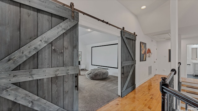 interior space featuring hardwood / wood-style flooring, lofted ceiling, and a barn door