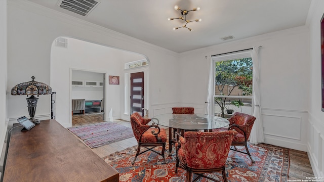 dining area featuring wood-type flooring, crown molding, and a notable chandelier