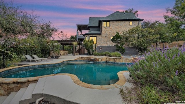 pool at dusk with a pergola and a patio area