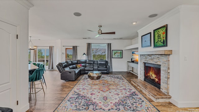 living room with ceiling fan with notable chandelier, a fireplace, ornamental molding, and hardwood / wood-style floors