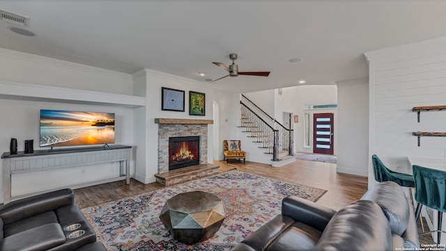 living room with a fireplace, ornamental molding, dark hardwood / wood-style floors, and ceiling fan