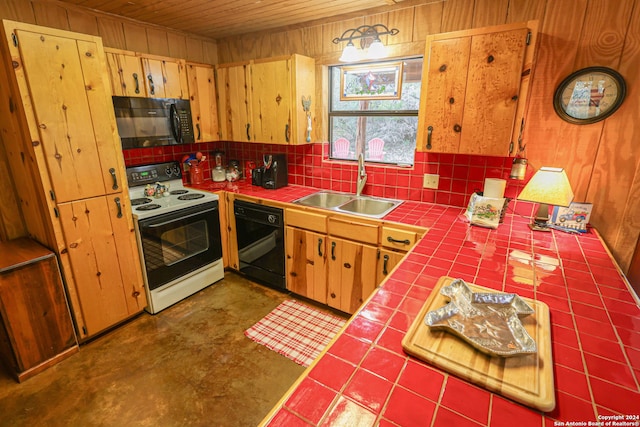 kitchen with tile countertops, wood walls, sink, and black appliances