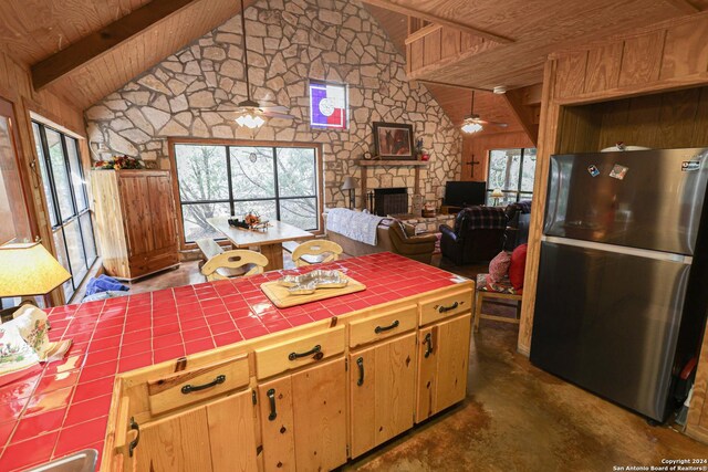 1177 River Rd, Concan, TX 78801 - kitchen with freestanding refrigerator, tile counters, wood ceiling, ceiling fan, and plenty of natural light