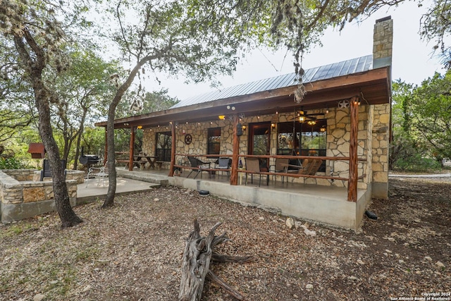 1177 River Rd, Concan, TX 78801 - back of property with stone siding, a chimney, metal roof, and a patio area