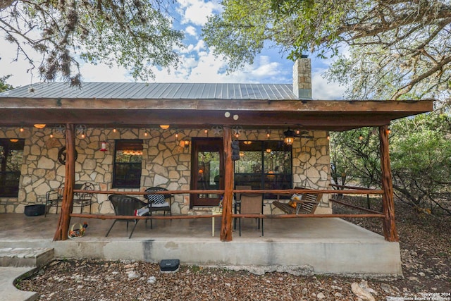 1177 River Rd, Concan, TX 78801 - rear view of house with stone siding, metal roof, a chimney, and a patio