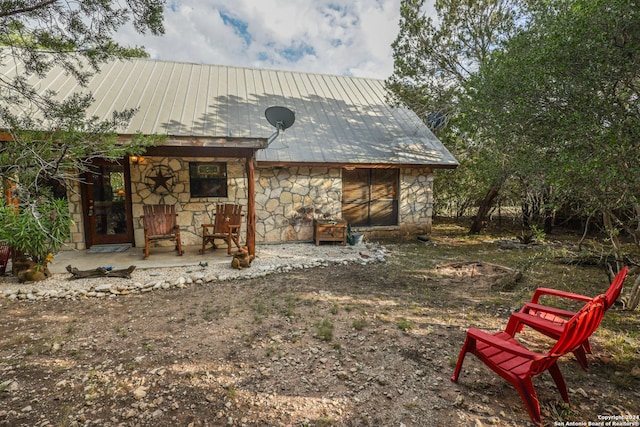 1177 River Rd, Concan, TX 78801 - back of house featuring stone siding, metal roof, and covered porch