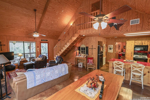 1177 River Rd, Concan, TX 78801 - living area with ceiling fan, wood walls, stairs, and high vaulted ceiling