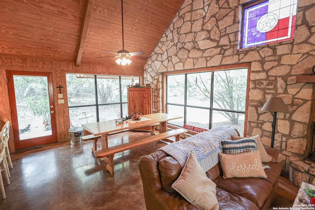 living room featuring lofted ceiling with beams, ceiling fan, wooden ceiling, concrete flooring, and wood walls