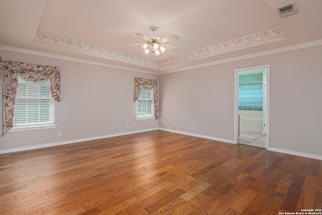 spare room featuring wood-type flooring, a raised ceiling, ornamental molding, and ceiling fan