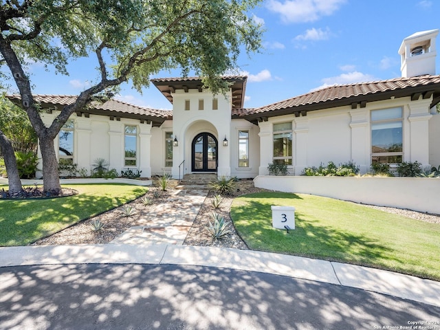 mediterranean / spanish home featuring french doors and a front yard