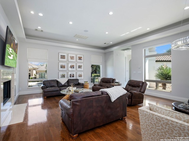 living room featuring dark wood-type flooring, a wealth of natural light, and a notable chandelier