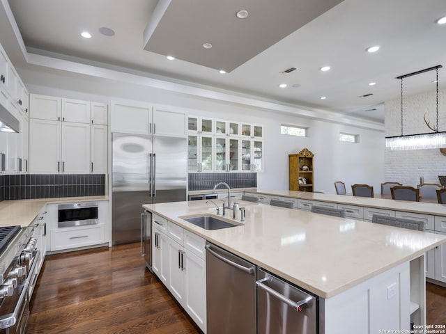 kitchen featuring white cabinets, high end appliances, and a kitchen island with sink