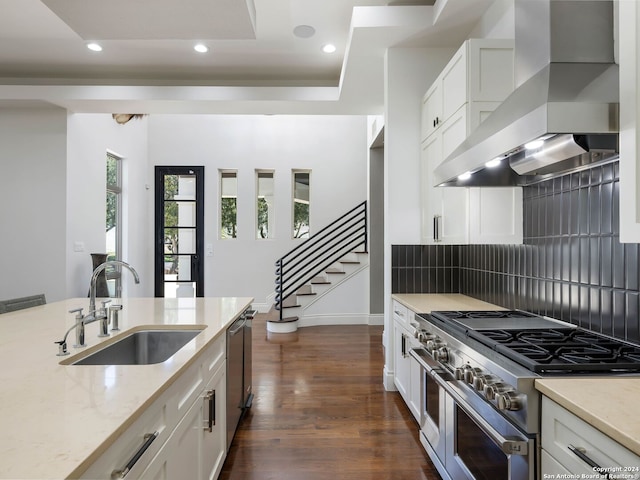 kitchen featuring white cabinetry, sink, appliances with stainless steel finishes, dark wood-type flooring, and wall chimney range hood