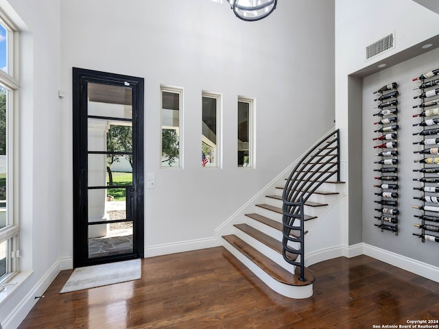 entryway featuring dark wood-type flooring, a wealth of natural light, and a towering ceiling