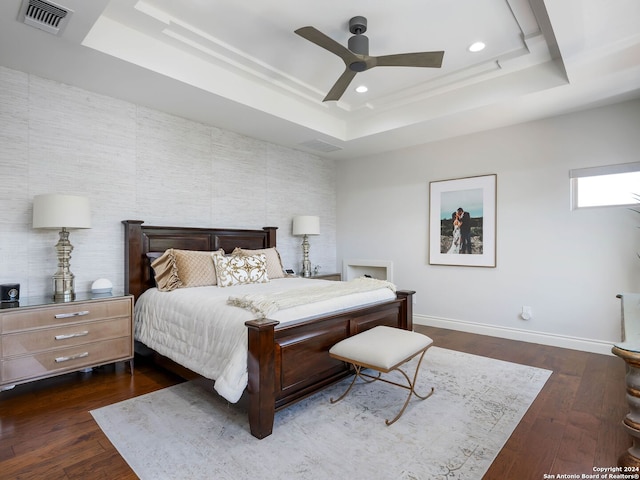 bedroom featuring dark wood-type flooring, ceiling fan, and a tray ceiling