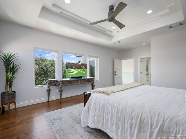 bedroom with ceiling fan, dark hardwood / wood-style floors, and a raised ceiling