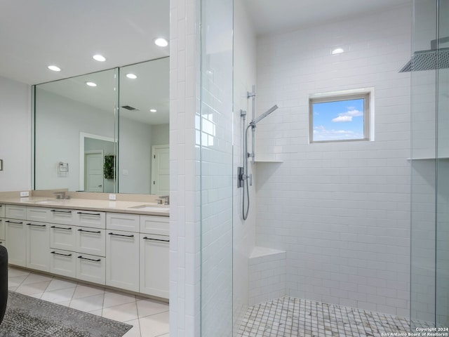 bathroom with tile patterned flooring, vanity, and a tile shower