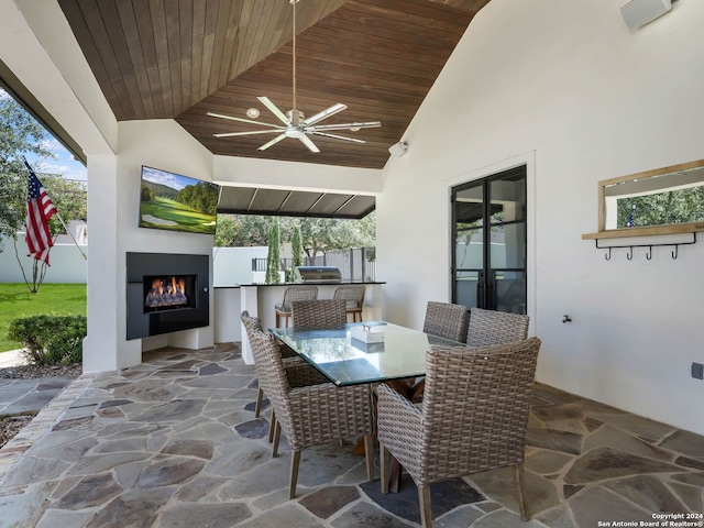 view of patio with an outdoor kitchen, an outdoor fireplace, and ceiling fan