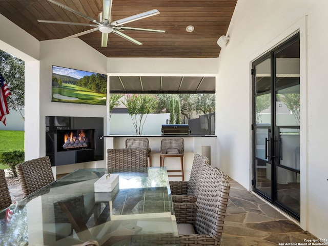 exterior space with exterior fireplace, ceiling fan, wood ceiling, and vaulted ceiling