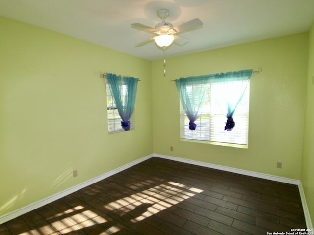 spare room with baseboards, ceiling fan, and dark wood-style flooring