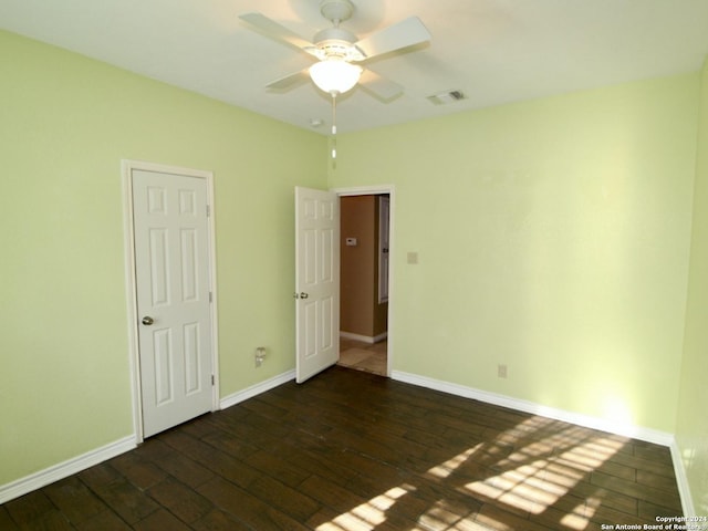 unfurnished bedroom with a ceiling fan, dark wood-style flooring, baseboards, and visible vents
