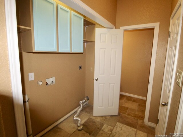 washroom with electric dryer hookup, stone finish floor, baseboards, cabinet space, and hookup for a washing machine