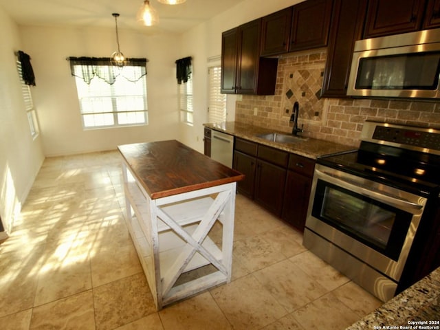 kitchen with dark stone counters, backsplash, a sink, and stainless steel appliances