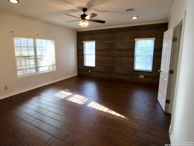 spare room featuring wooden walls, ceiling fan, and a wealth of natural light