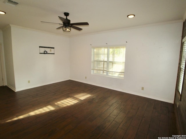 empty room featuring dark wood-style floors, baseboards, visible vents, ceiling fan, and ornamental molding