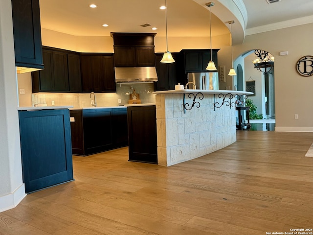 kitchen featuring light hardwood / wood-style floors, exhaust hood, decorative light fixtures, ornamental molding, and stainless steel fridge