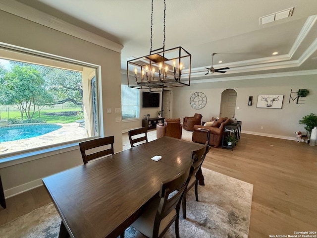 dining area featuring ceiling fan, hardwood / wood-style flooring, a raised ceiling, and crown molding