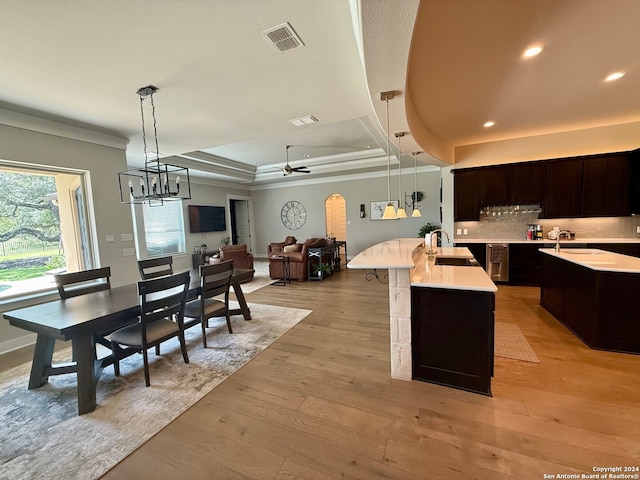 kitchen with ceiling fan with notable chandelier, light hardwood / wood-style floors, hanging light fixtures, and sink