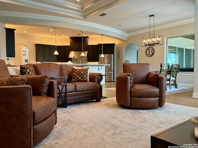 living room with light hardwood / wood-style flooring, a notable chandelier, and crown molding