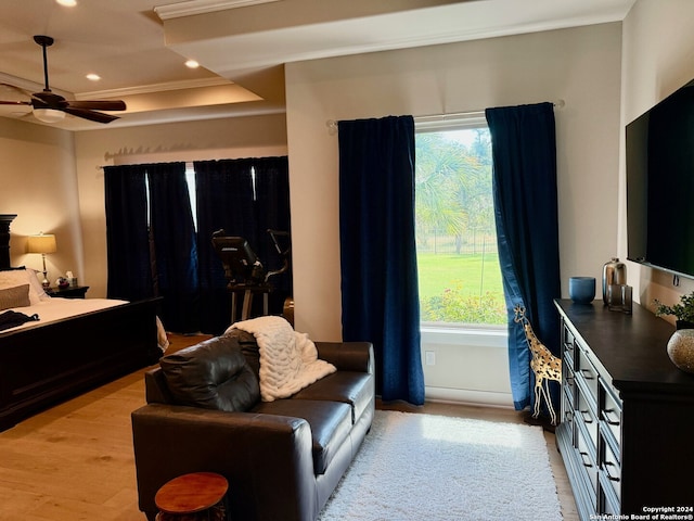 bedroom featuring light hardwood / wood-style flooring, multiple windows, a raised ceiling, and ornamental molding