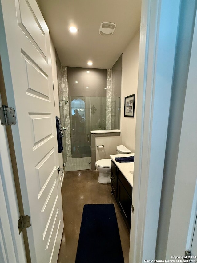 bathroom featuring concrete floors, a shower with door, vanity, and toilet