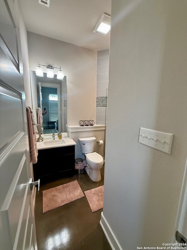 bathroom featuring concrete flooring, vanity, and toilet