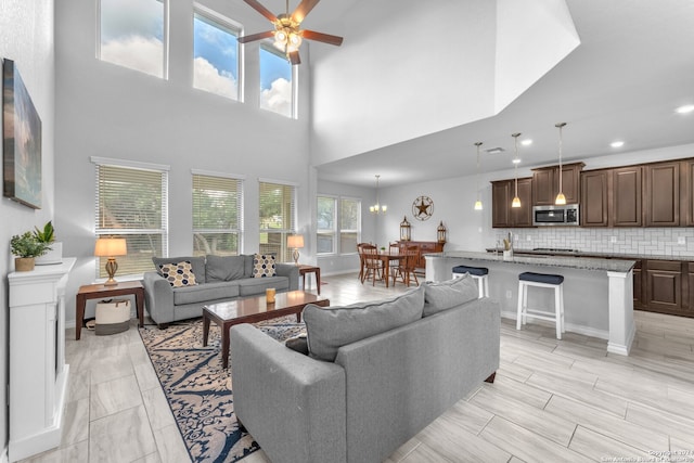 living room with a high ceiling and ceiling fan with notable chandelier