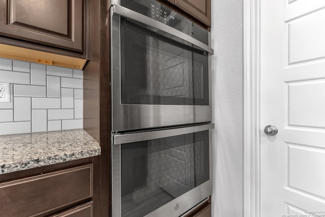 details featuring double oven, tasteful backsplash, light stone countertops, and dark brown cabinets