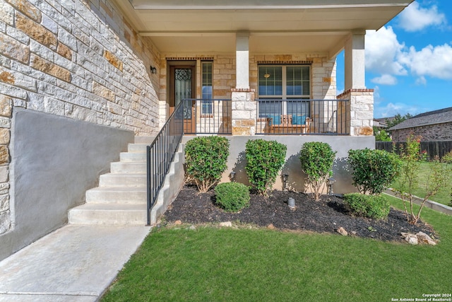 doorway to property with a porch and a yard