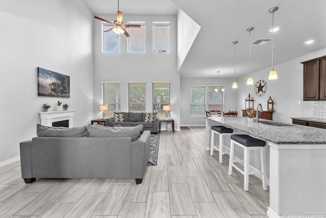 living room featuring ceiling fan, plenty of natural light, a high ceiling, and sink